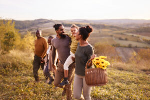 A happy multigenerational family walks through a sunlit field, symbolizing lifelong health and well-being.